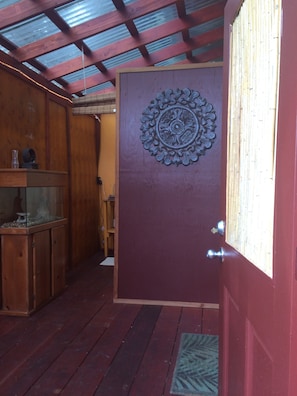 A wooden interior with a red door, a decorative metal plate, and a wooden cabinet with a glass enclosure.