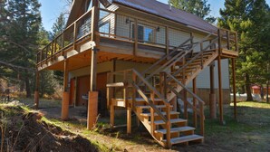 A two-story wooden cabin with a balcony and a staircase leading to the upper level. - Welcome to our Rock Creek Fortress of Solitude. (Philipsburg)