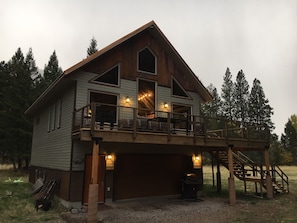 A two-story wooden house with a balcony, a garage, and a staircase leading to the upper level.