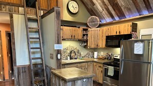 A rustic kitchen with wooden cabinets, a stainless steel refrigerator, a stone backsplash, and a wooden ladder. - Welcome to our Rock Creek Fortress of Solitude. (Philipsburg)
