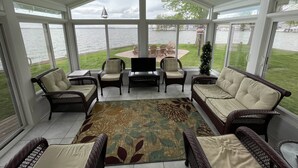 Un patio cubierto con mobiliario de mimbre, un televisor de pantalla plana y vistas al lago.