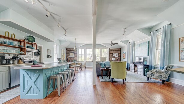 Una cocina amplia con una isla central, suelo de madera y una zona de comedor con sillas y una mesa.