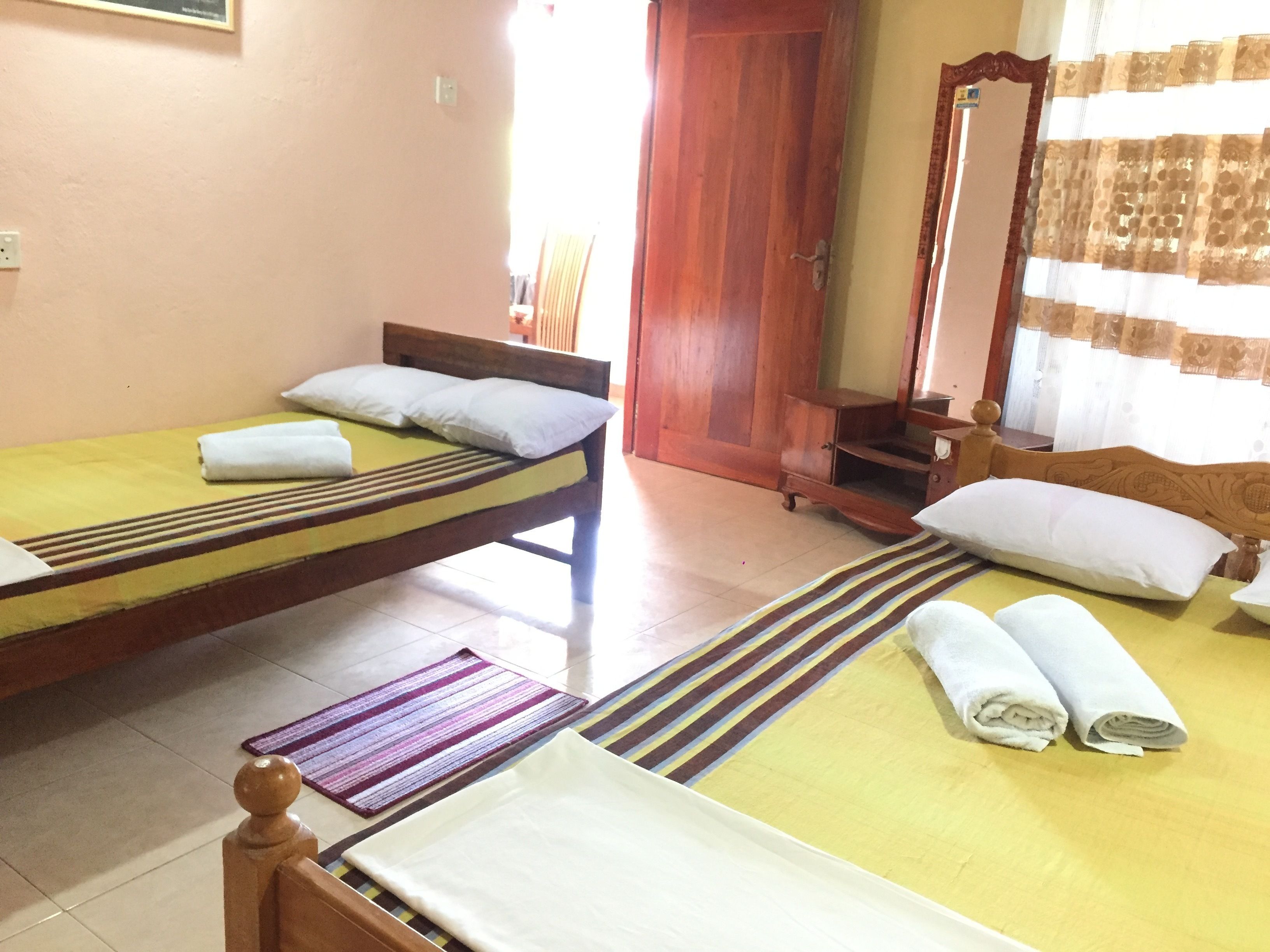 Una habitación con dos camas individuales, un armario de madera, un espejo y una puerta.