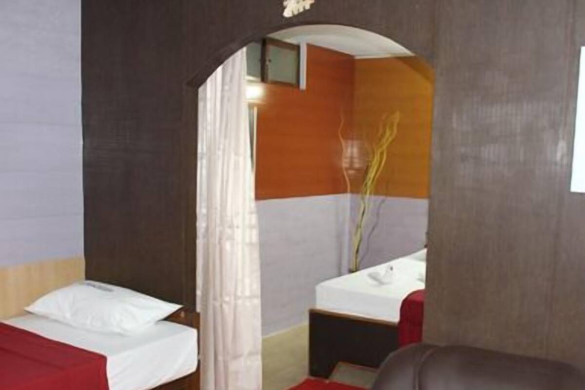 A hotel room with two beds, a sitting area, and a bathroom.