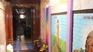 A hallway with a mirror, potted plants, and a wall mural. - Suradeep Residency (Tirukalukundram)