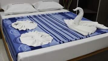 A hotel room with a bed featuring a blue and white striped bedspread, two white pillows, and two white towels arranged on the bed.