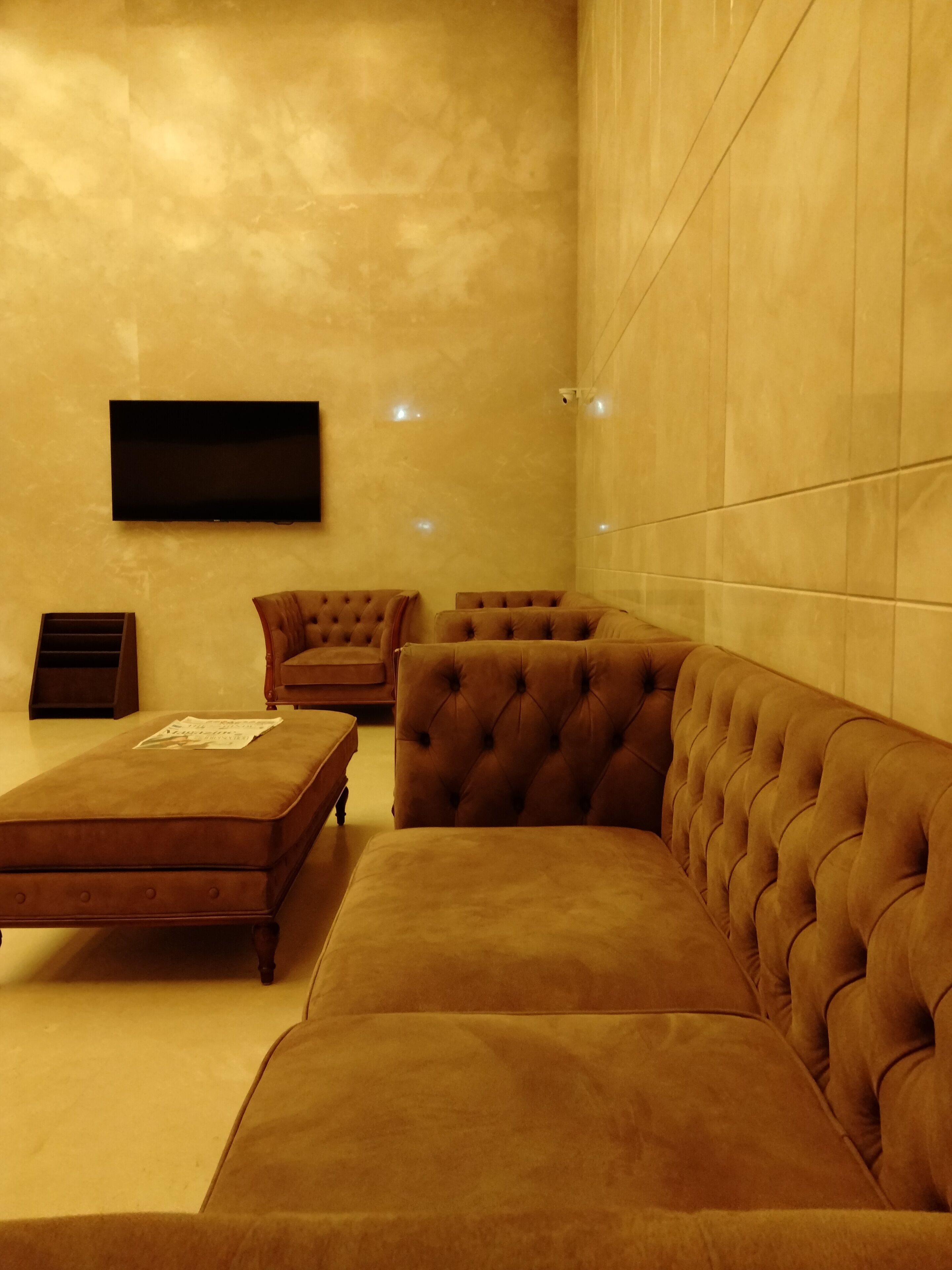 Una sala de estar moderna con un sofá grande tipo seccional, un sillón pequeño y un televisor de pantalla plana montado en la pared.