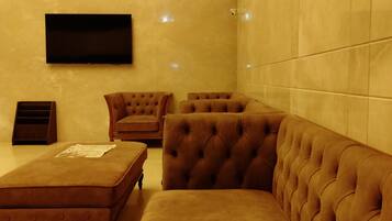 Una sala de estar moderna con un sofá grande tipo seccional, un sillón pequeño y un televisor de pantalla plana montado en la pared.