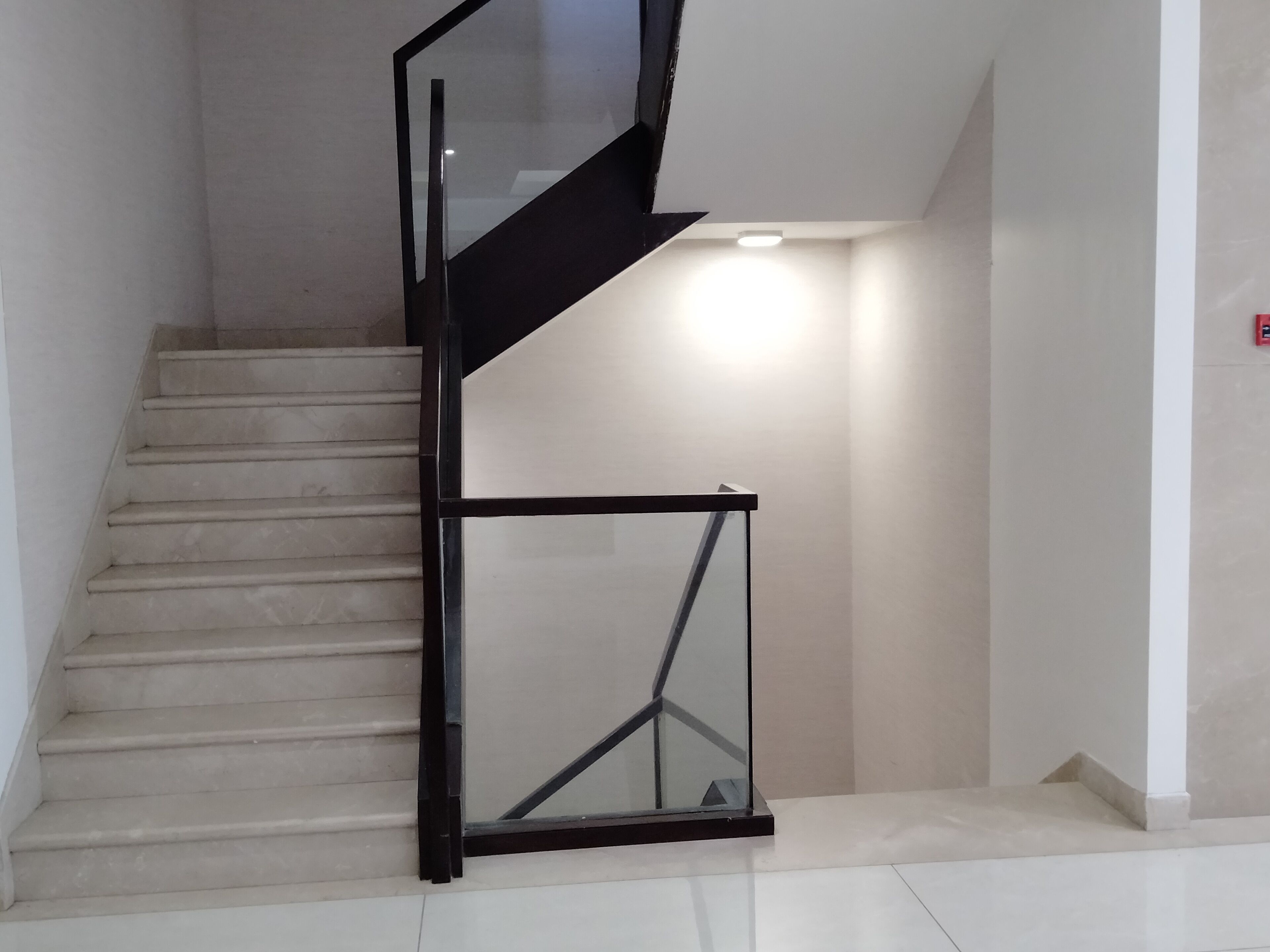 A modern staircase with a glass railing and a light fixture at the top.