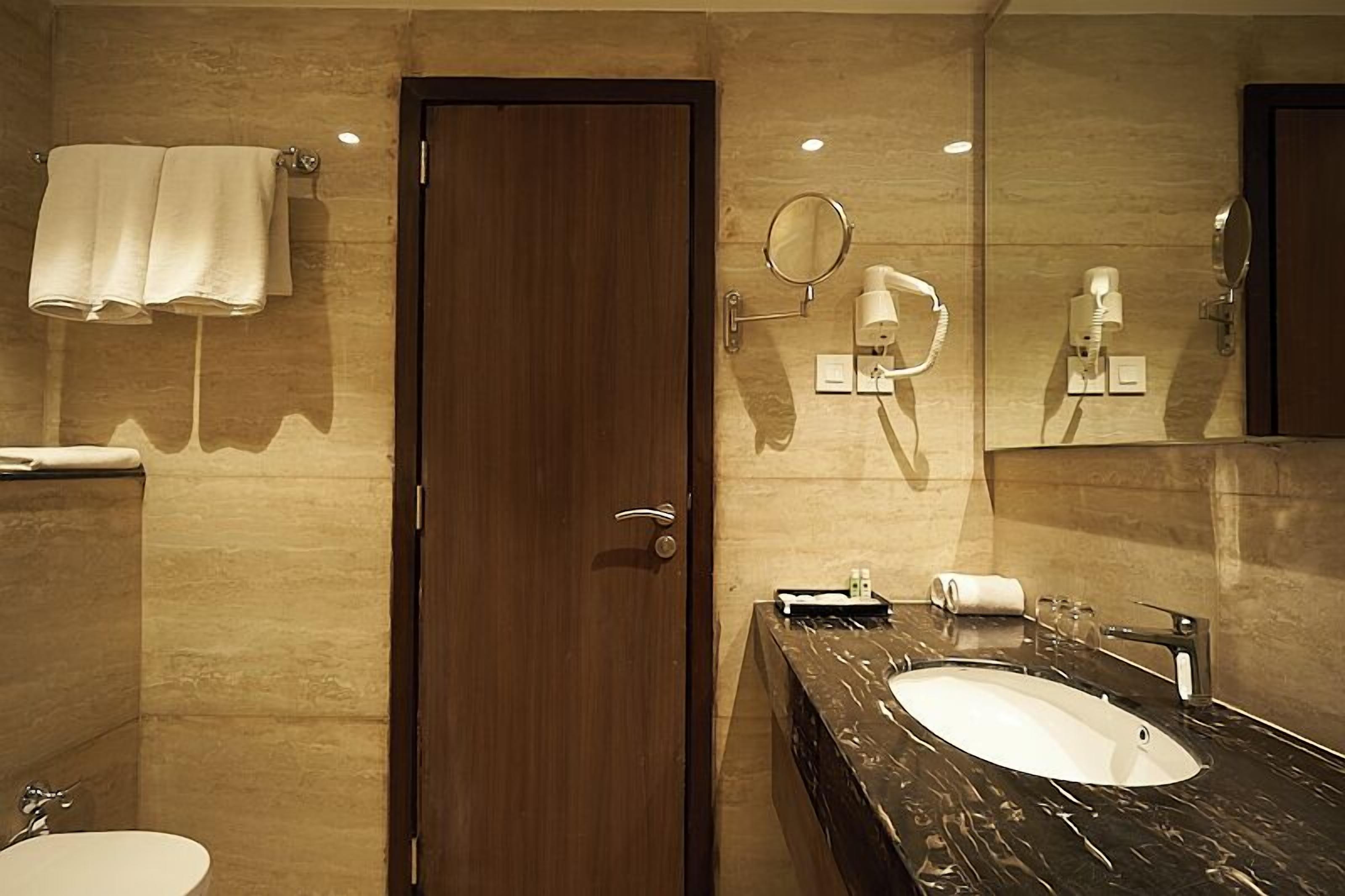 A modern bathroom with a marble sink, a mirror, a towel rack, and a toilet.
