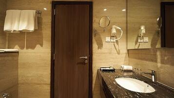Un baño moderno con lavamanos de mármol, un espejo, un perchero para toallas y un inodoro.
