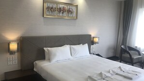 A hotel room with a large bed, two bedside lamps, a framed artwork above the bed, and a chair by the window. - The Hamuse Hotel Kodaikanal - Luxury Redefined (Kodaikanal)