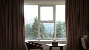 A room with a window, a chair, a small table, and a tissue box. - The Hamuse Hotel Kodaikanal - Luxury Redefined (Kodaikanal)