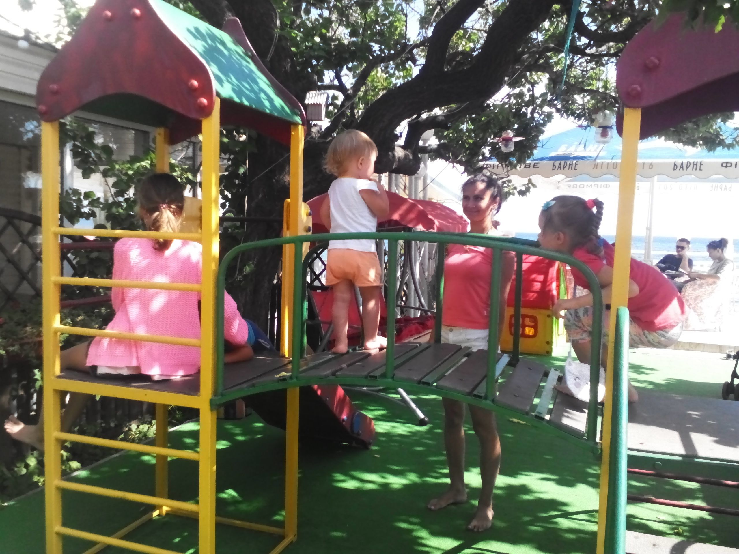 A playground with a yellow and red play structure, including a swing and a climbing area.
