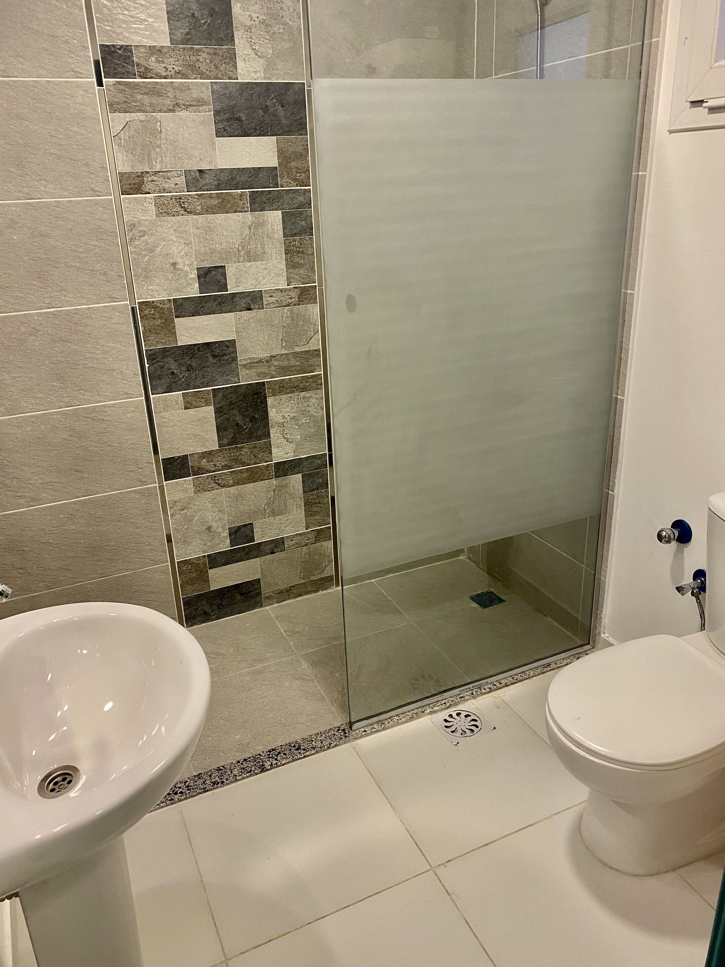 A bathroom with a shower, a sink, and a toilet.