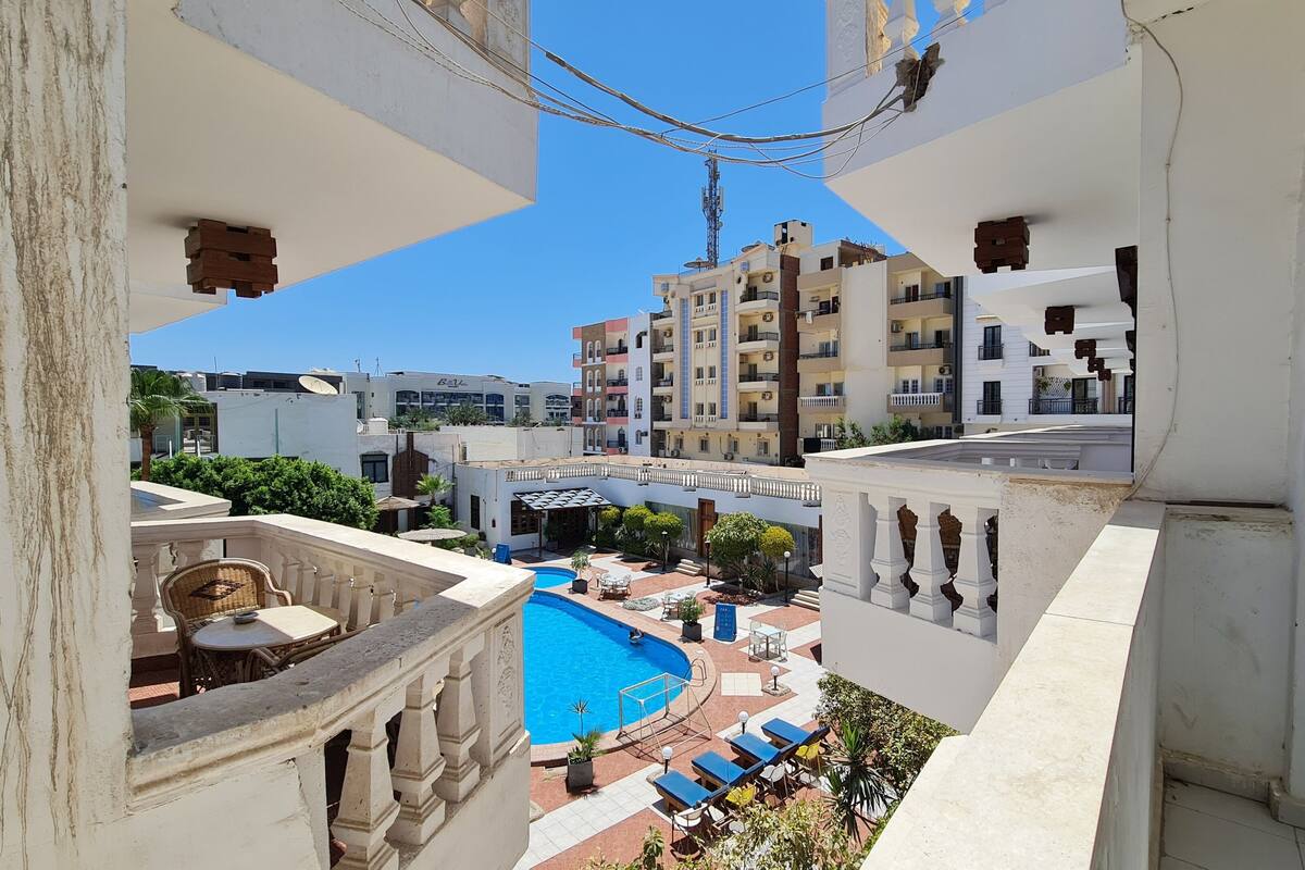 A view of a residential area with a swimming pool, balconies, and a clear blue sky.