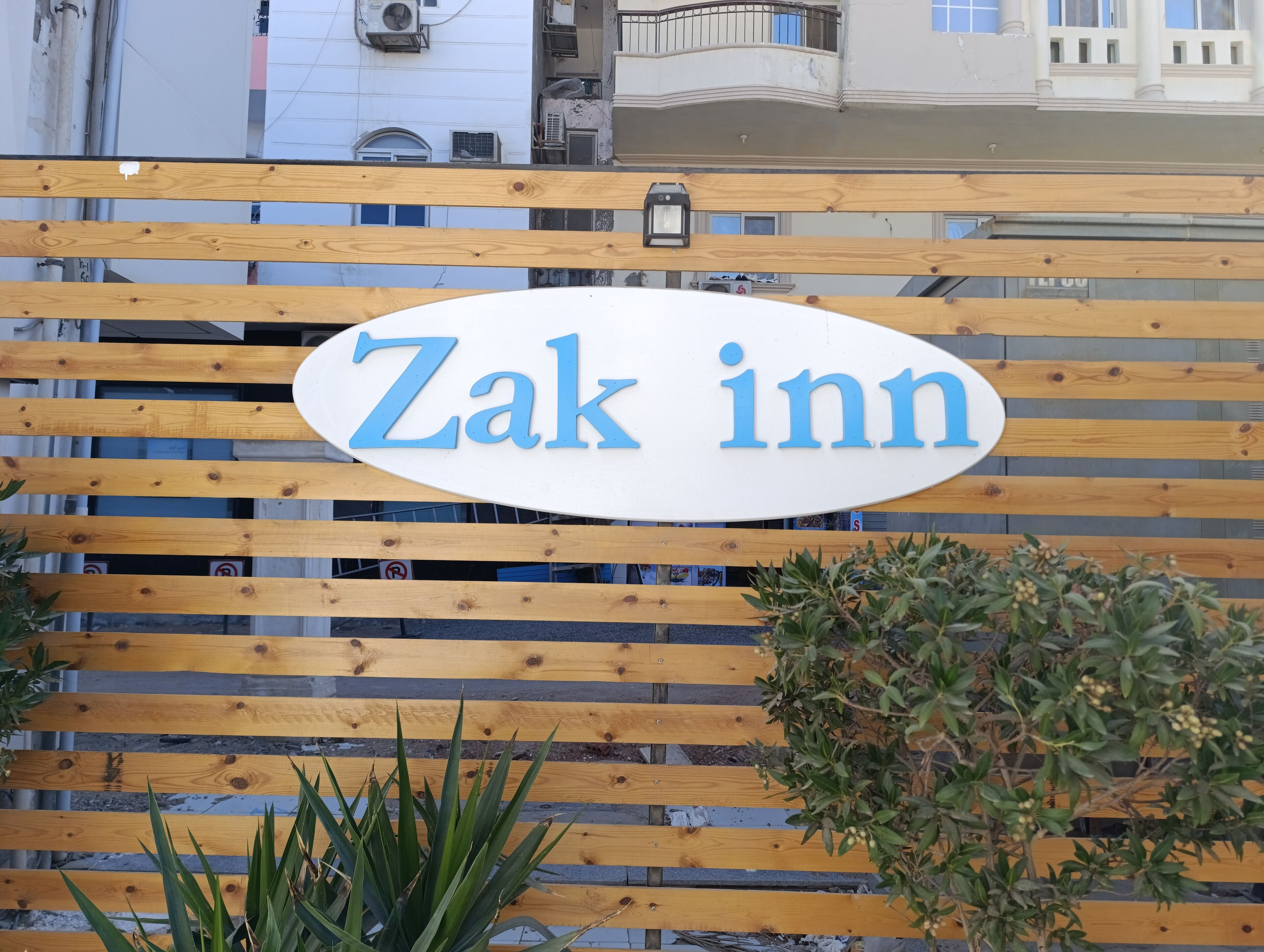 Ein Holzzaun mit einem Schild, auf dem 'Zak Inn' steht.