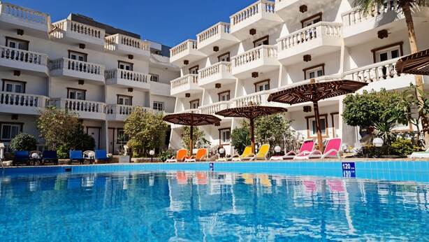 Un hotel con piscina, varios balcones y zonas de estar al aire libre.