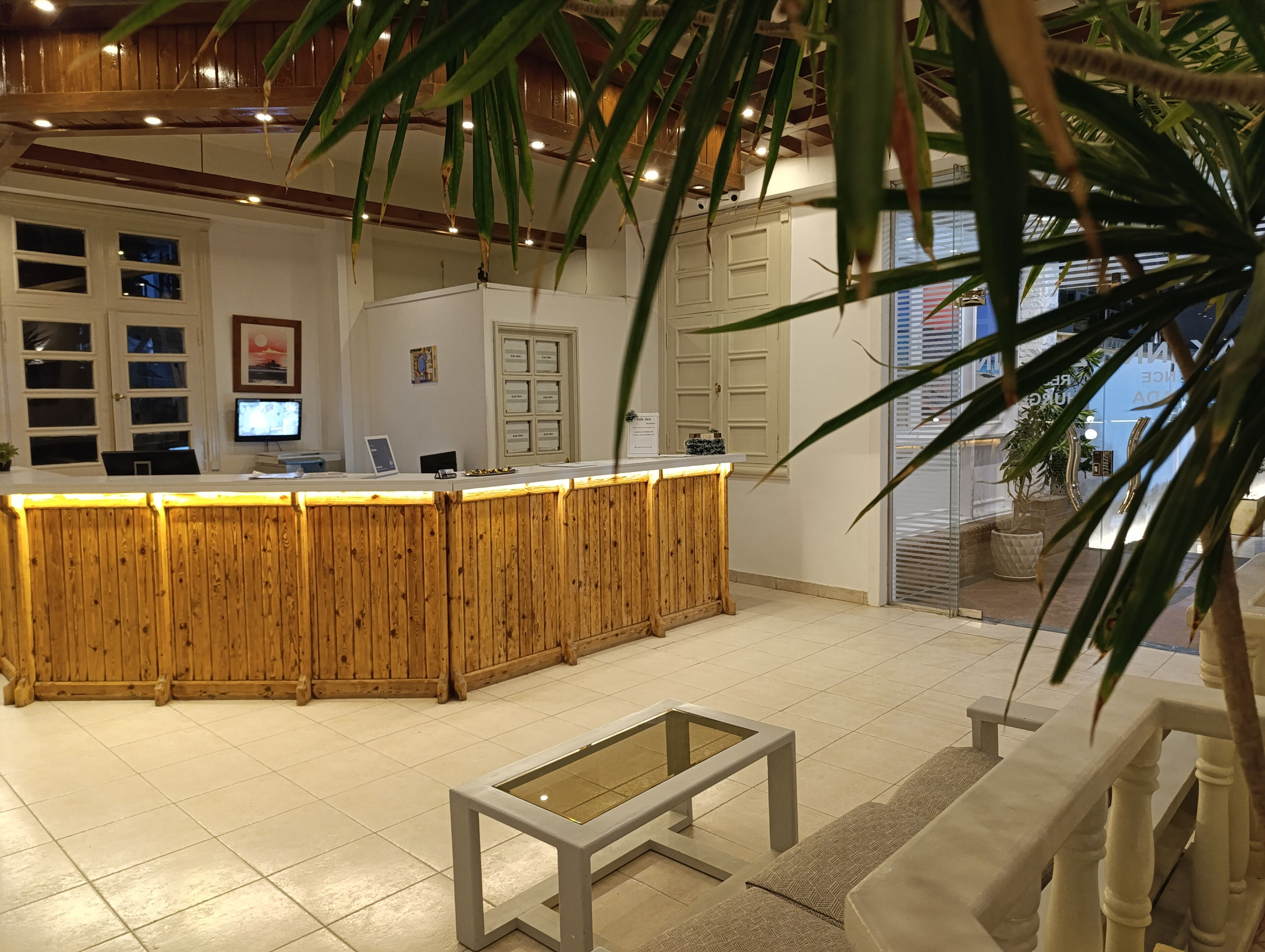 Un'area reception con un bancone in legno, un tavolino da caffè con piano in vetro e un divano.