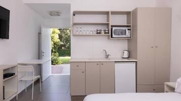 Una camera d'albergo moderna e minimalista con un letto, una scrivania, angolo cottura e vista sull'esterno.