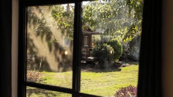 Une vue à travers une fenêtre donnant sur une structure en bois dans un jardin.