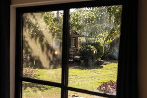 A view through a window with a wooden structure in a garden.