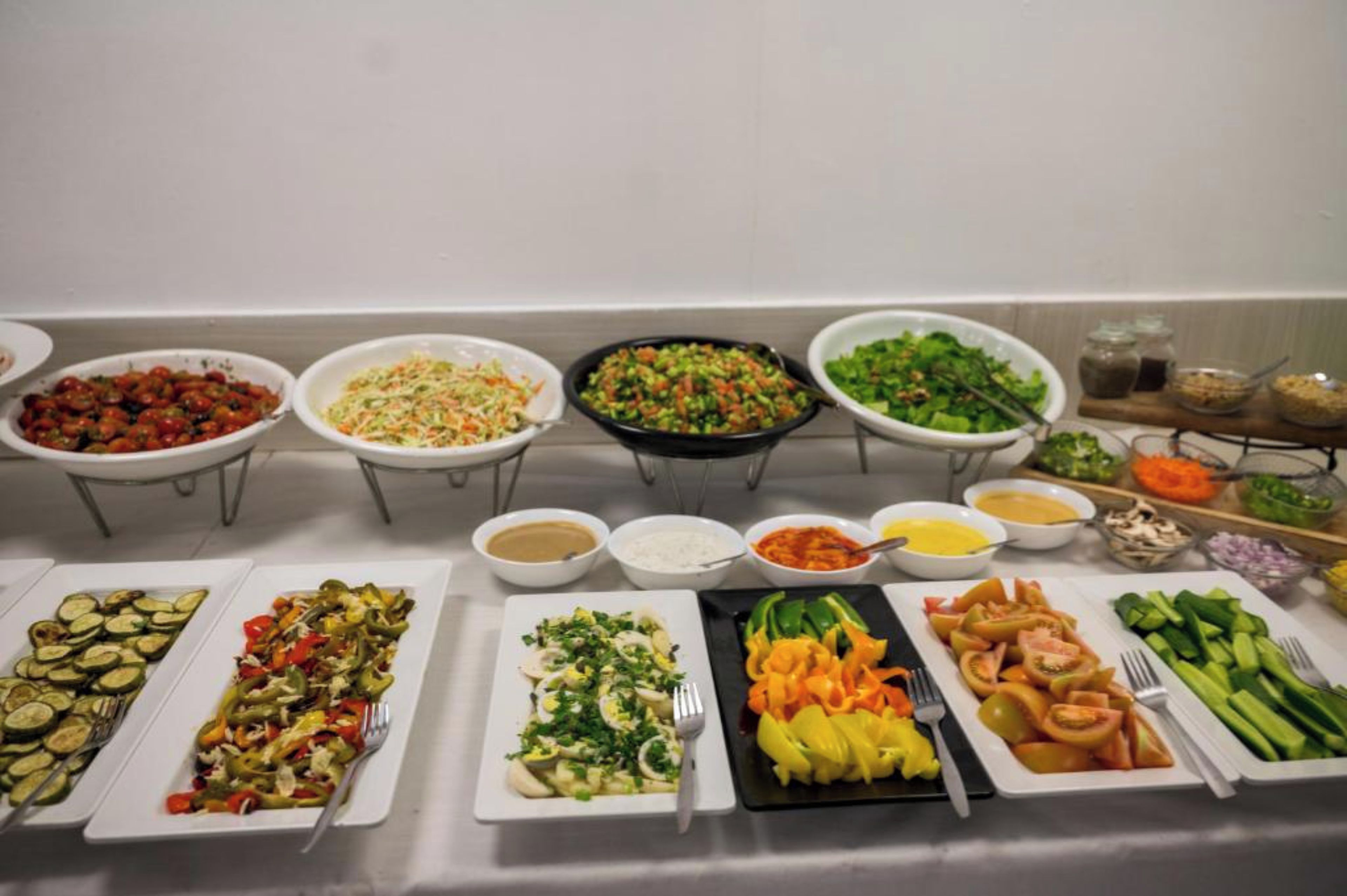 Una mesa de buffet con diversos platos, entre ellos ensaladas, verduras y arroz.