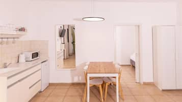 A compact kitchen with a dining table, white cabinets, and a microwave.