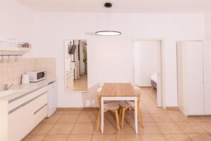 A compact kitchen with a dining table, white cabinets, and a microwave. - Nofey Habashan Country Lodge (HaGalil HaElyon)