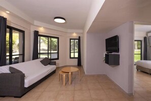 A modern living room with a sofa, a coffee table, and a flat-screen TV mounted on the wall. - Nofey Habashan Country Lodge (HaGalil HaElyon)