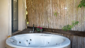 A spa area with a large white bathtub, a wooden deck, and a bamboo wall. - Nofey Habashan (HaGalil HaElyon)