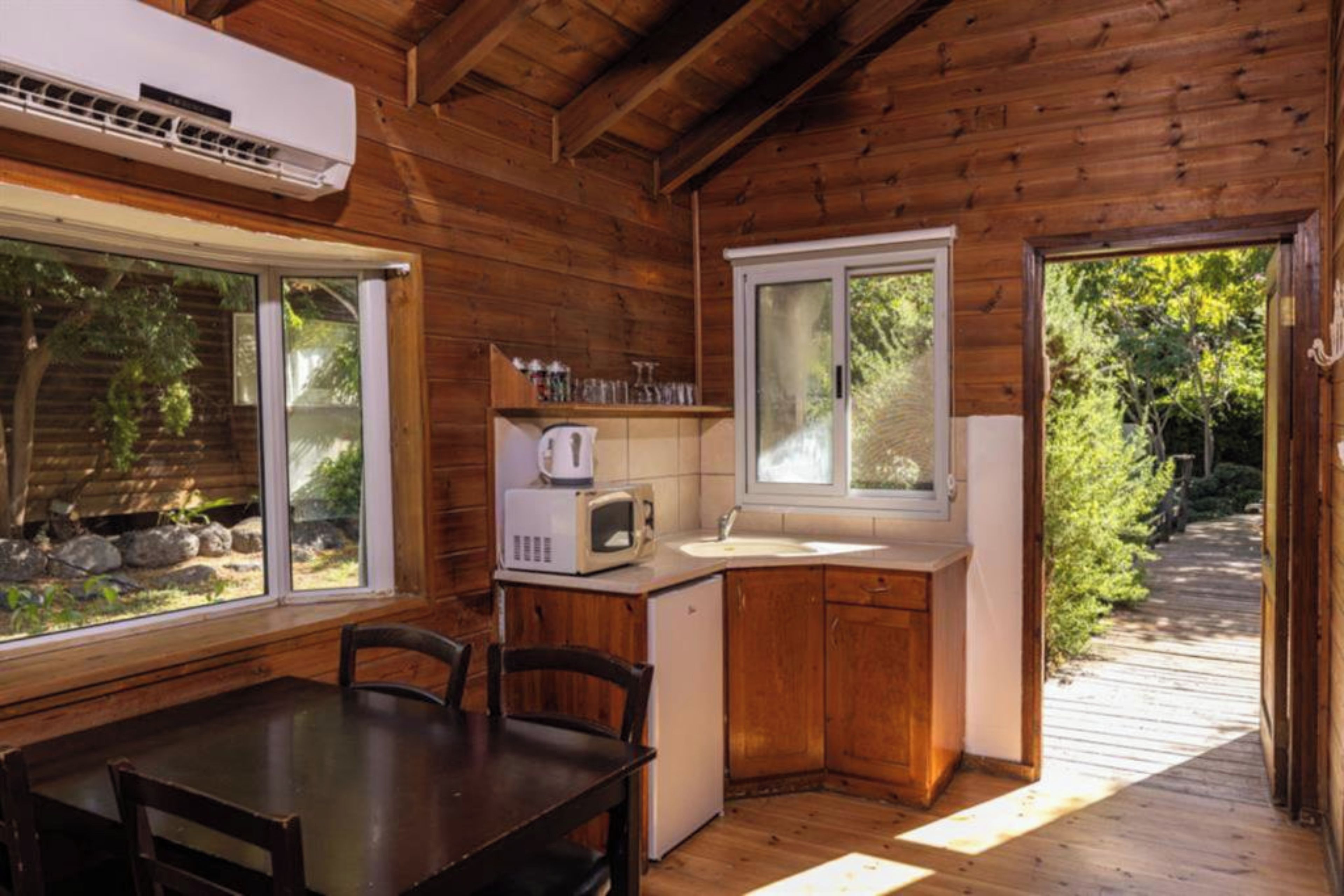 Une cabane en bois équipée d’une table à manger, de chaises, d’un four à micro-ondes et d’un évier.