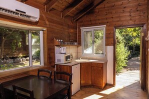 Uma cabana de madeira com uma mesa de jantar, cadeiras, micro-ondas e pia.