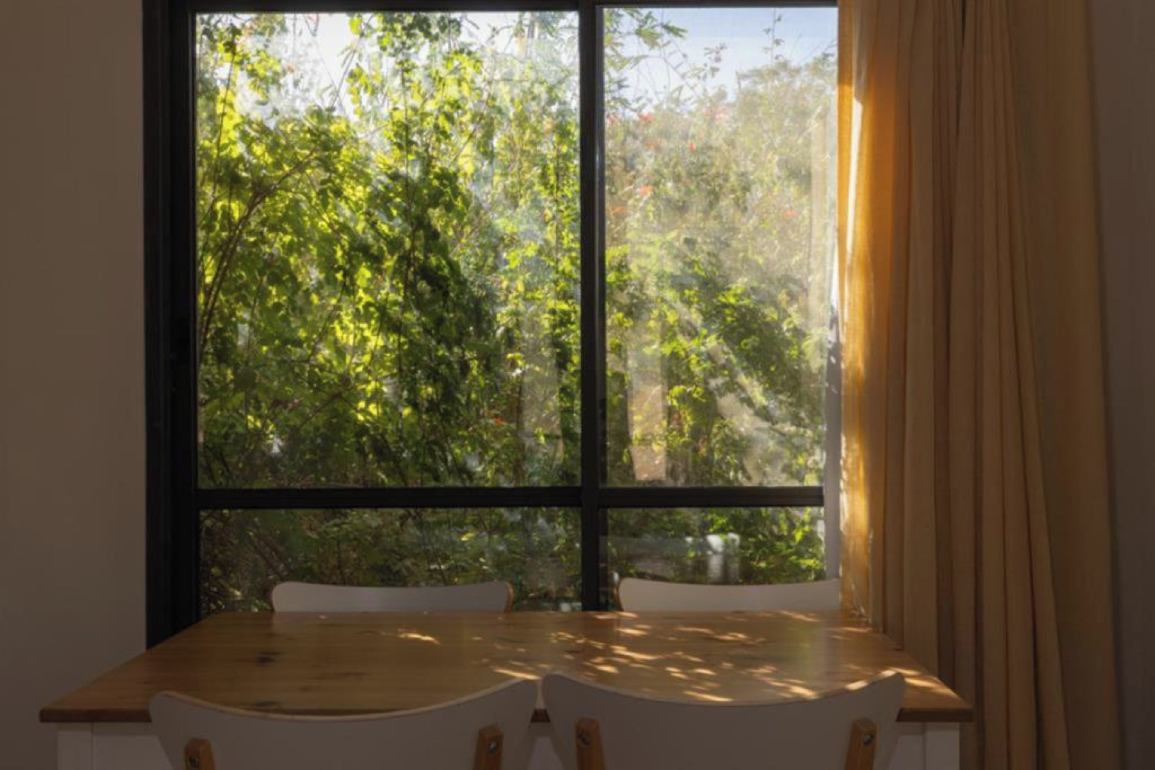 Ein Zimmer mit großem Fenster, einem Holztisch und einem Stuhl.