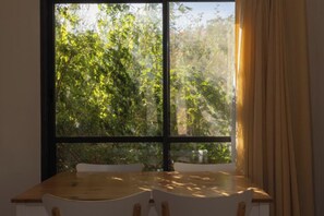 Um quarto com uma janela grande, uma mesa de madeira e uma cadeira.