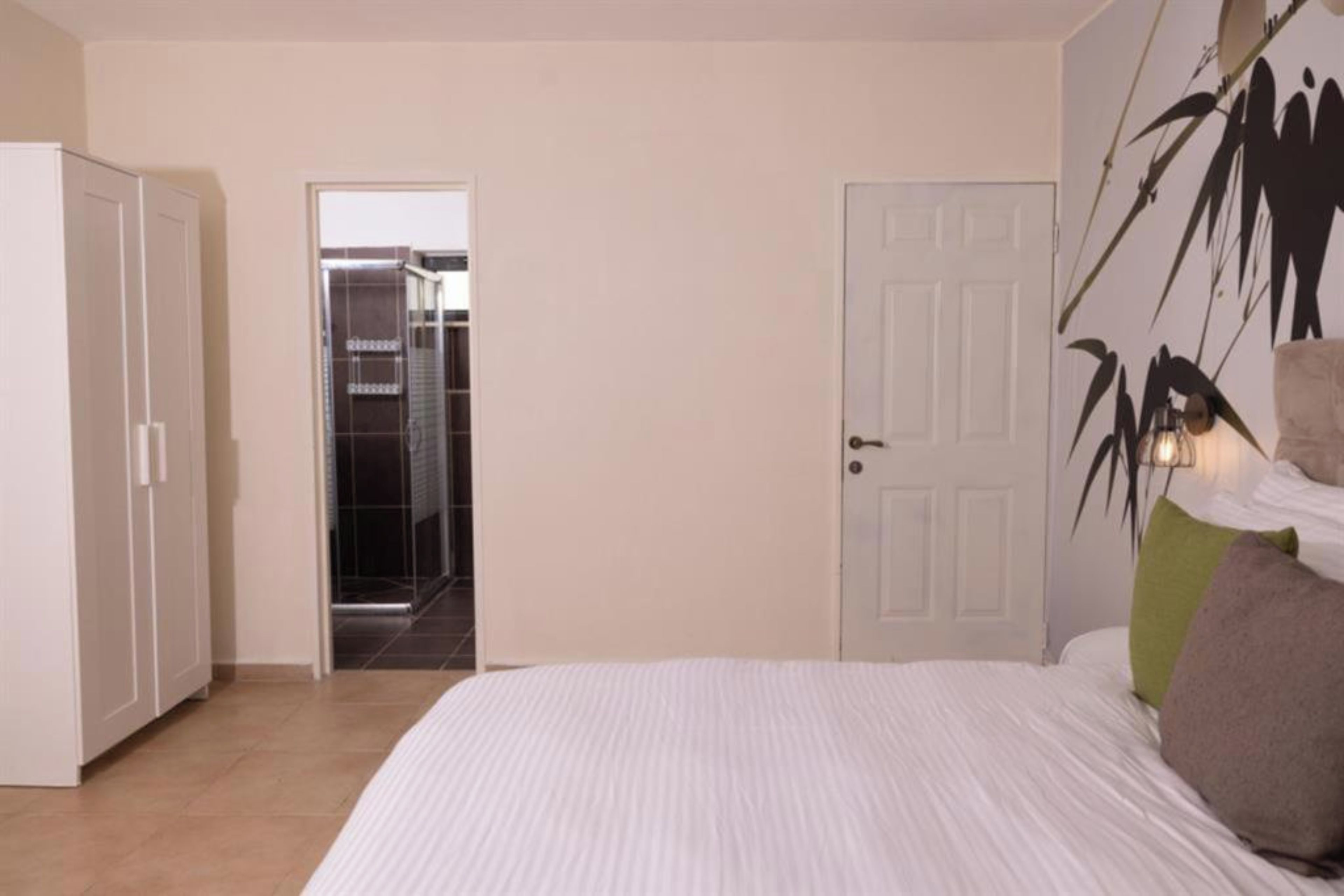 A bedroom with a bed, a wardrobe, and a door leading to a bathroom.