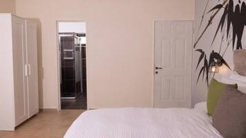 A bedroom with a bed, a wardrobe, and a door leading to a bathroom.