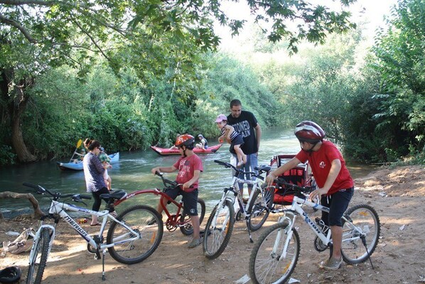 A group of people near a river with bicycles, a canoe, and a motorboat. - Nofey Habashan (HaGalil HaElyon)