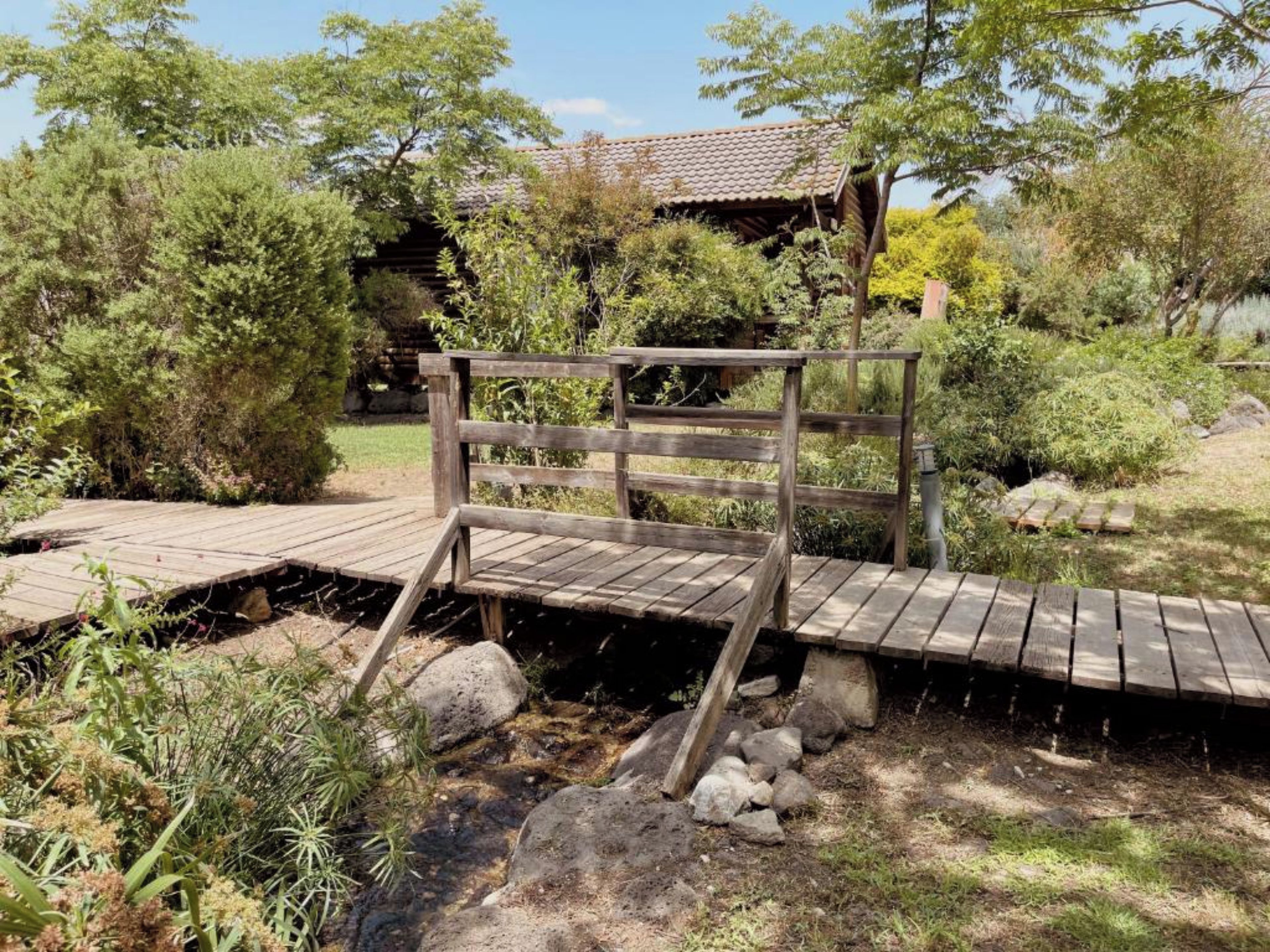 Un pont en bois enjambant un ruisseau, avec un banc en bois installé dessus.