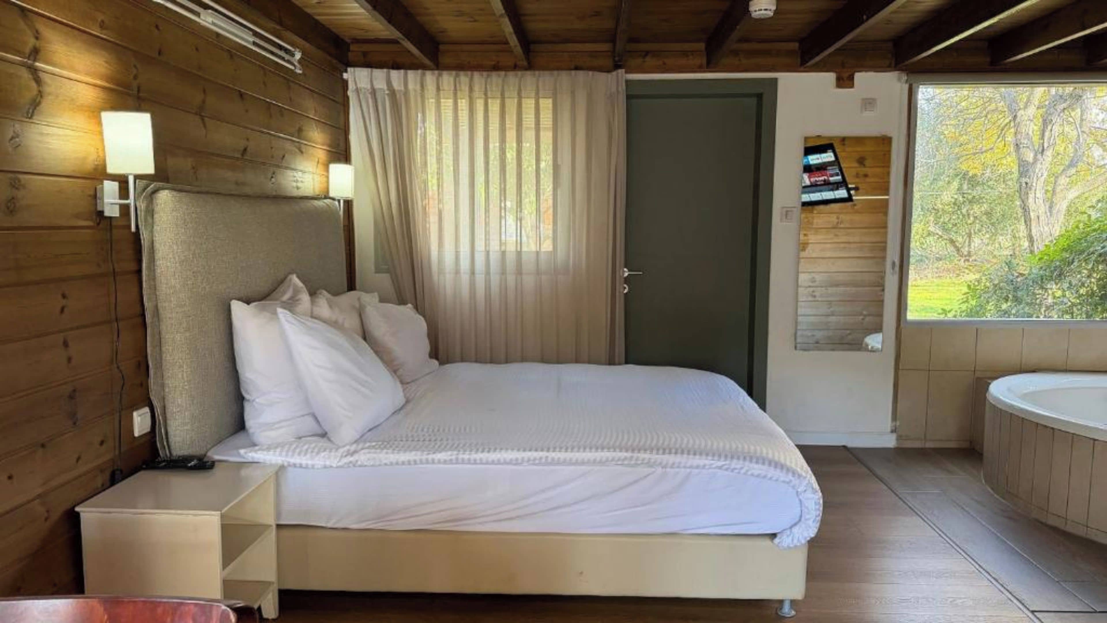 Un dormitorio con cama, lámparas de noche, una puerta y vistas al exterior.