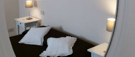 Una habitación con una cama, dos mesitas de noche y un espejo.