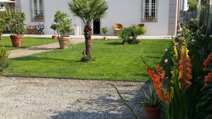 A white building with a tiled roof, a gravel driveway, and potted plants. - Villa Armonia (Lucca)
