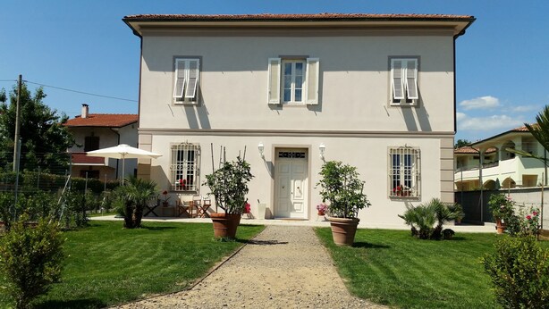 A two-story building with a central entrance, potted plants, and a gravel pathway. - Villa Armonia (Lucca)