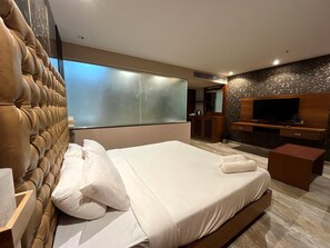 Relax in a stylish room with a tufted headboard, flat-screen TV, and kitchenette.
