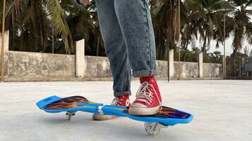 A person standing on a skateboard with a concrete surface and palm trees in the background.