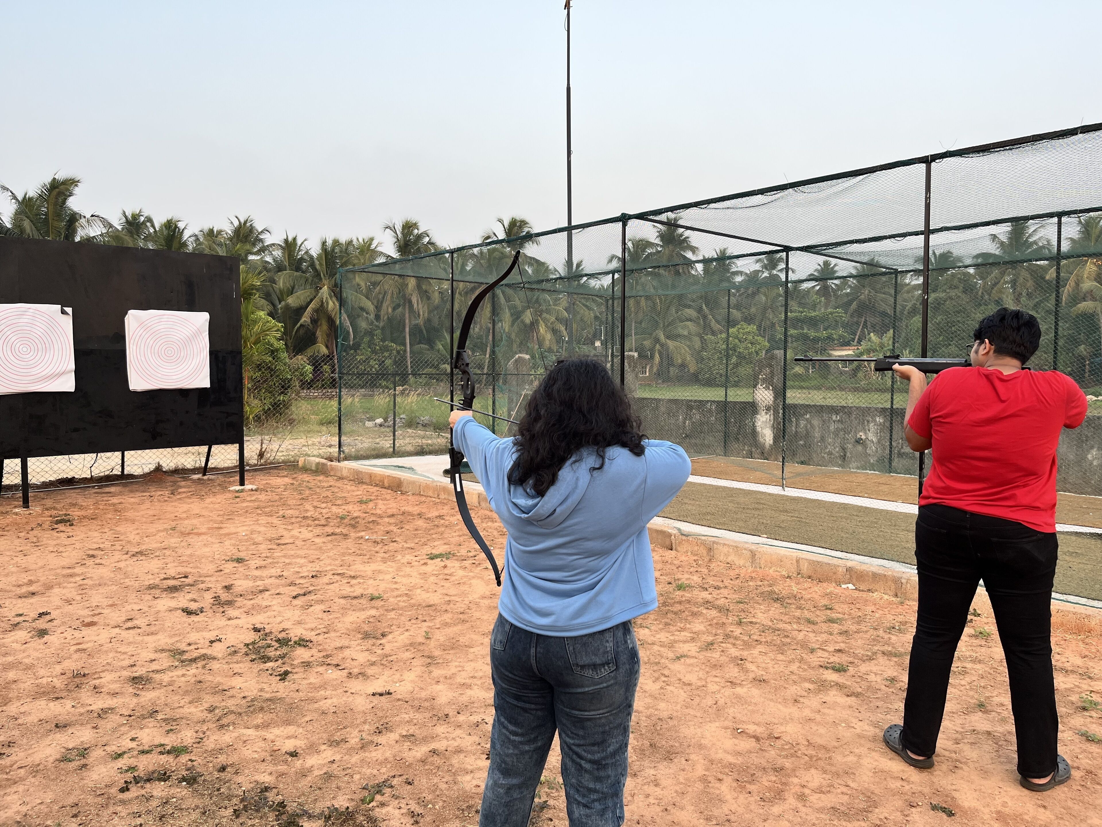 An outdoor shooting range with targets and a netted enclosure.