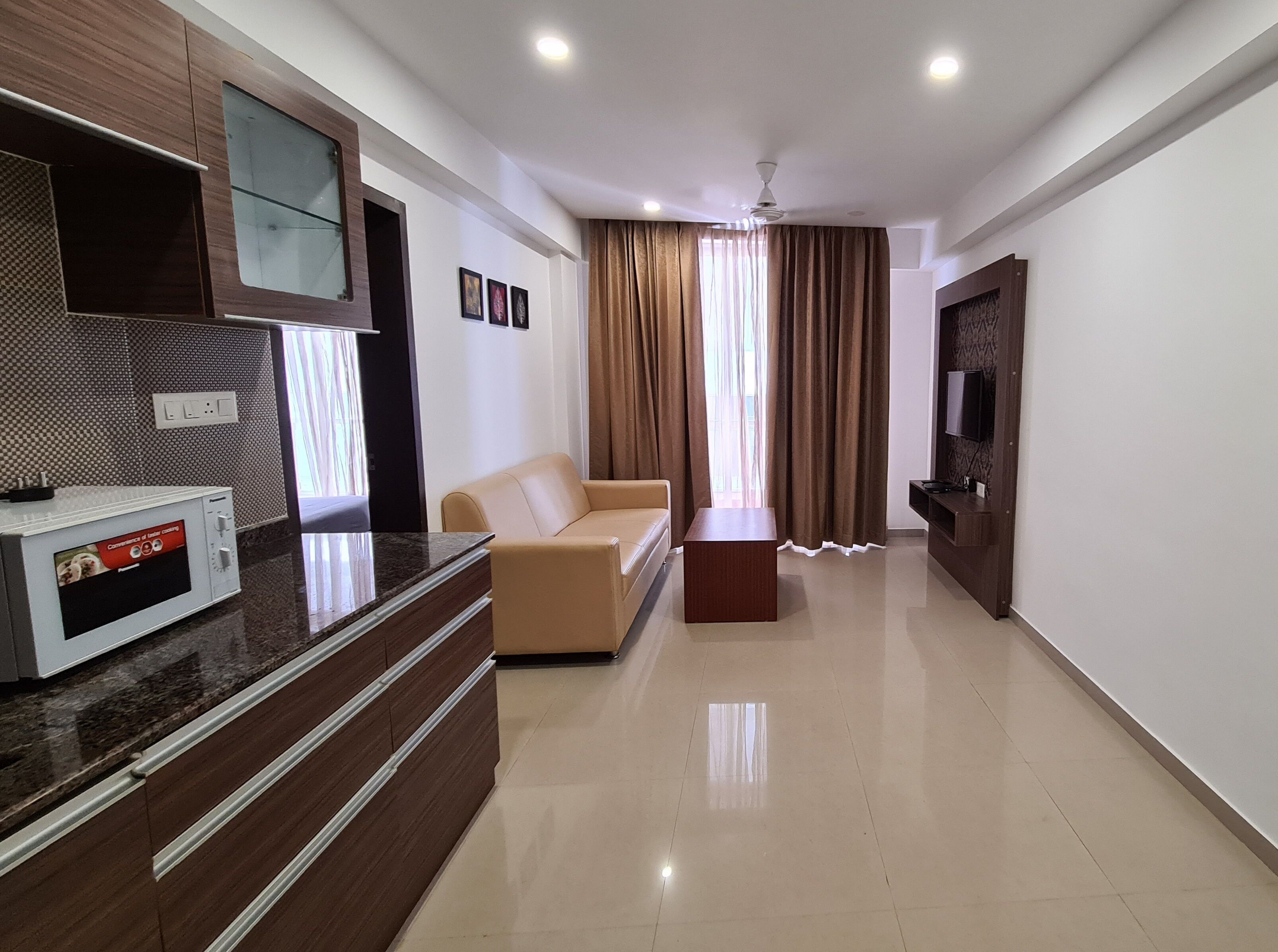 A modern living room with a sofa, a coffee table, a flat-screen TV, and a built-in microwave.