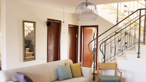 A living room with a sofa, a wooden chair, a coffee table, and a staircase with a metal railing. - Nahal Faran 32 (Ramat Negev)
