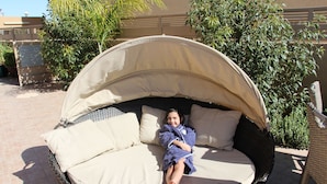 A wicker outdoor seating area with a canopy, cushioned seating, and a small table. - Nahal Faran 32 (Ramat Negev)