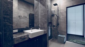 Une salle de bain moderne avec un grand miroir, un lavabo blanc, des meubles de rangement sombres et une cabine de douche en verre.